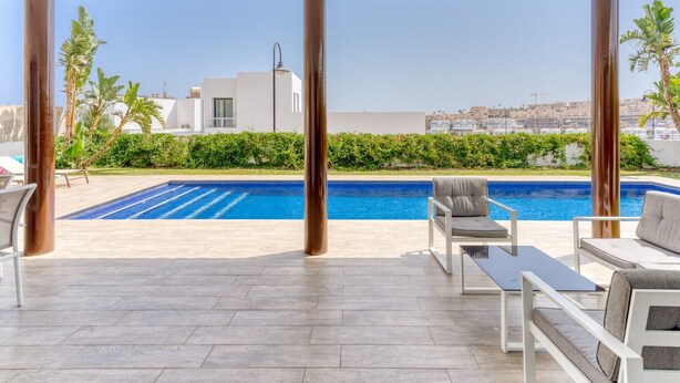 Un espacio al aire libre cubierto con piscina, sillas de descanso y vistas a un paisaje urbano.