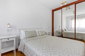 A bedroom with a bed, bedside tables, a mirror, and a wardrobe.
