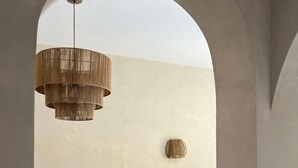 Un comedor con una mesa de madera dispuesta para dos personas, una lámpara colgante y vistas a través de un arco.