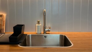 Una cocina moderna con un lavamanos de acero inoxidable, encimera de madera y una lámpara fijada a la pared.