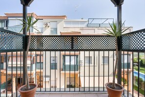 A balcony with potted plants, a view of a residential building, and a clear sky. - Apartment 'Camaleón 7' with Shared Pool, Private Terrace and Air Conditioning (Chipiona)