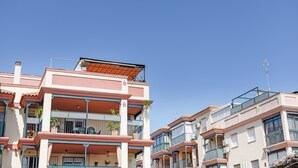 Un immeuble résidentiel à plusieurs étages, doté de balcons, d’un toit plat et surplombant un ciel d’un bleu limpide.