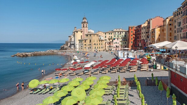 Un pueblo costero con playa, edificios y una torre.