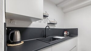 Una cocina moderna con encimeras negras, un hervidor de acero inoxidable, un fregadero y una estantería para vinos.