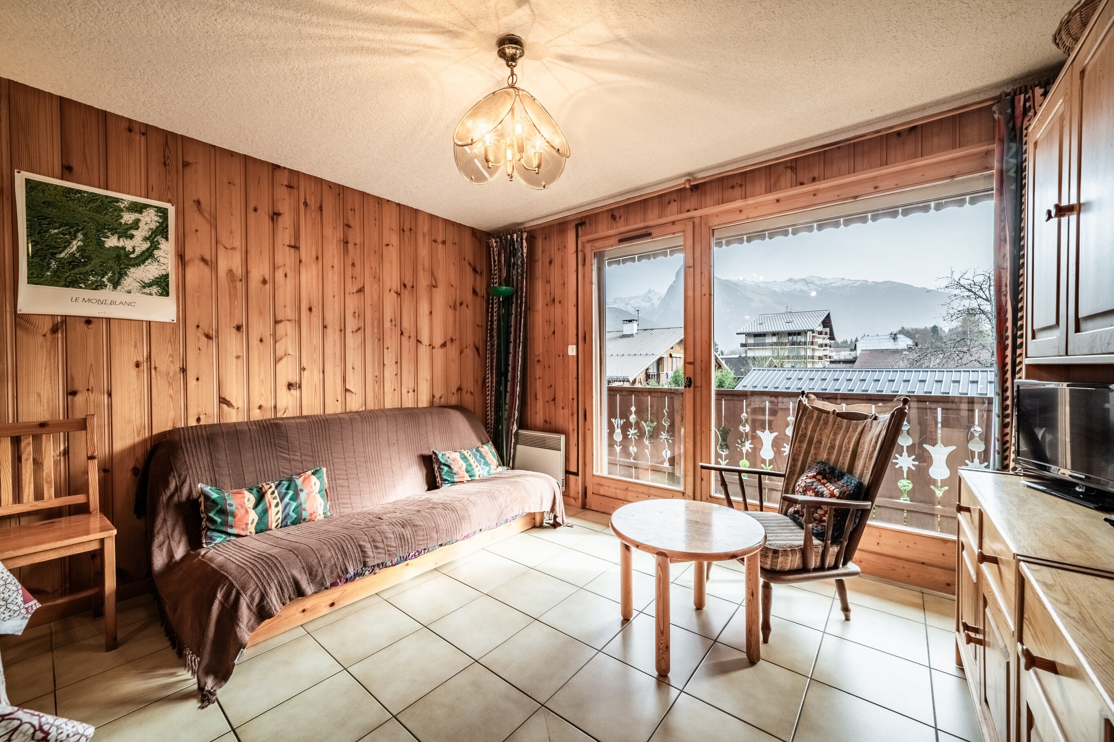 A wooden interior with a sofa, a chair, a table, and a TV.