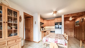 Una cocina con armarios de madera, una mesa de comedor con mantel y un ventilador de techo.