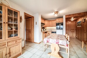 Una cocina con armarios de madera, una mesa de comedor con mantel y un ventilador de techo.