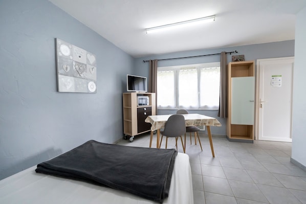 Une pièce comprenant un lit, un bureau avec un ordinateur, une chaise, une table et une armoire.