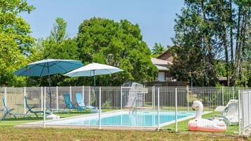 A swimming pool with lounge chairs, a swan float, and a fenced area.