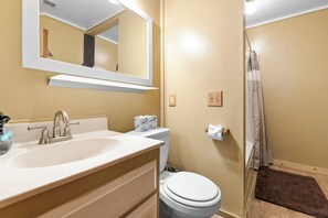 A bathroom with a sink, mirror, toilet, and shower curtain. - Brown Bear Inn (Big Bear Lake)