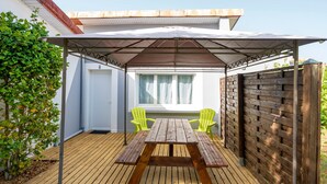 Une terrasse en bois avec une table de pique-nique et des chaises, un patio couvert et une clôture en bois.