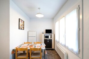 A compact kitchen with a dining table, chairs, a refrigerator, a microwave, and a window with curtains. - "Bruyères - Domaine Des Landes" with shared pool, private terrace, and shared garden (Lesperon)