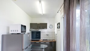 Eine kleine Küche mit Kühlschrank, Mikrowelle, Herd und einem Esstisch.
