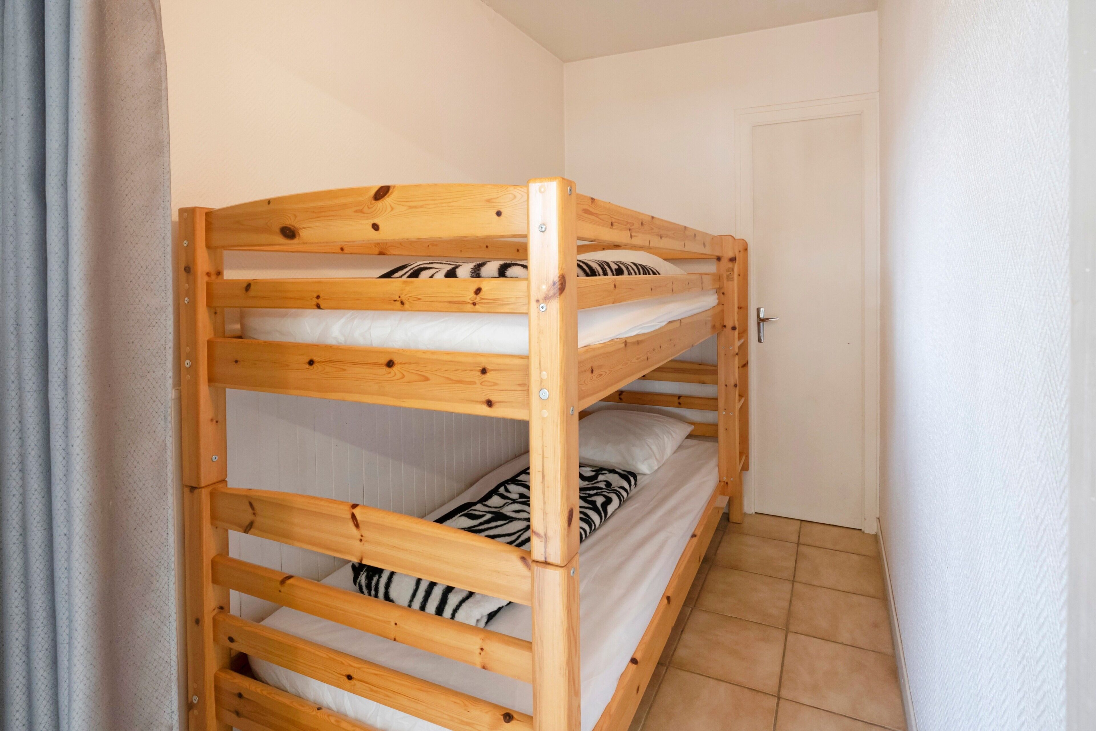 Una cama litera con un cojín estampado con diseño de cebra y una puerta blanca al fondo.