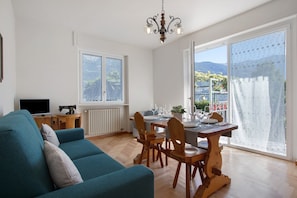 Un salon comprenant un canapé, une table à manger, des chaises, un téléviseur et un radiateur.