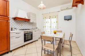 A kitchen with a dining table, chairs, a TV, and a window with curtains. - Apartment 'Da Lorenzo  Alcantara' with Mountain View and Wi-Fi (Gaggi)