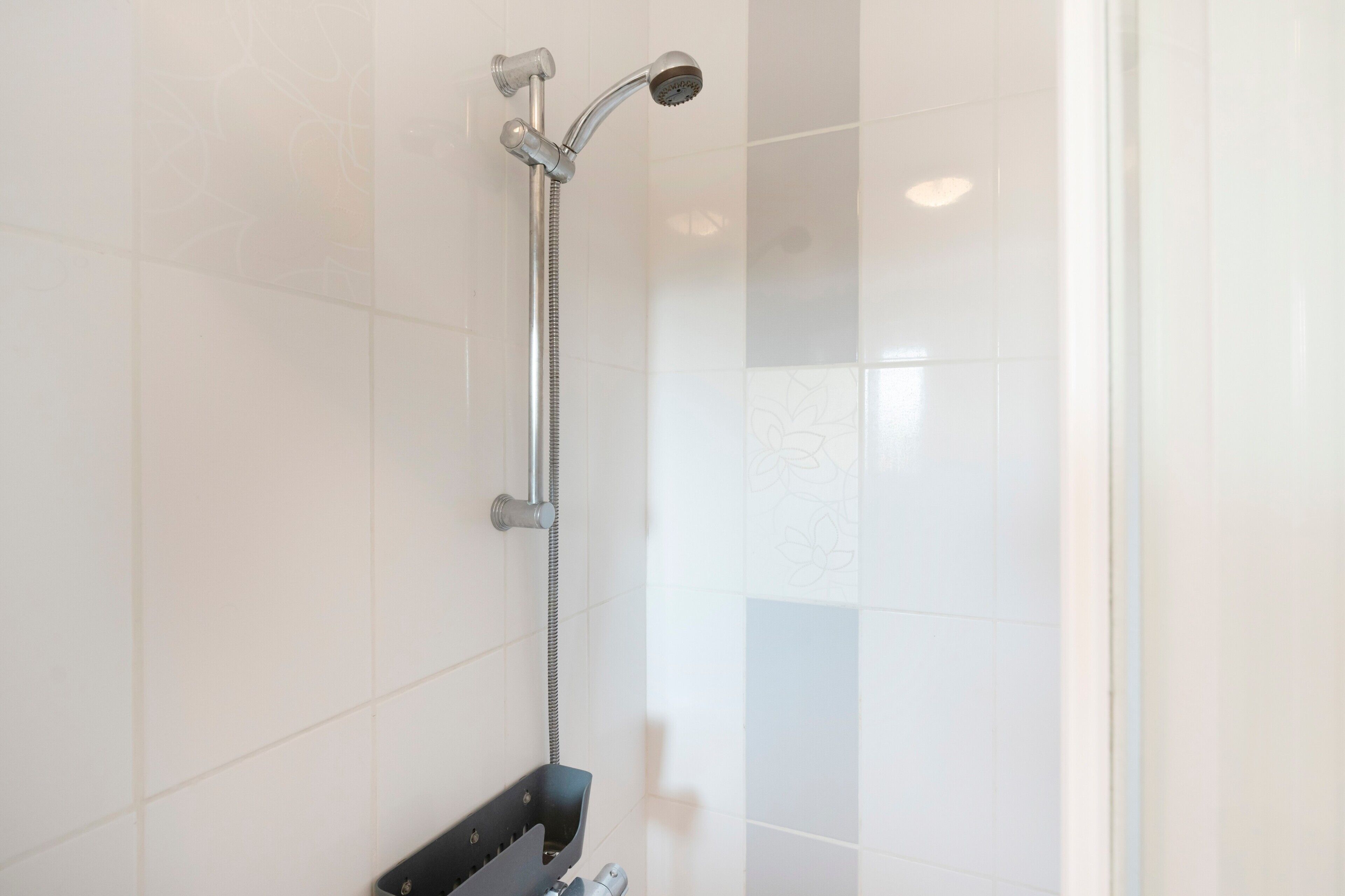 A shower with a handheld showerhead and a wall-mounted faucet.