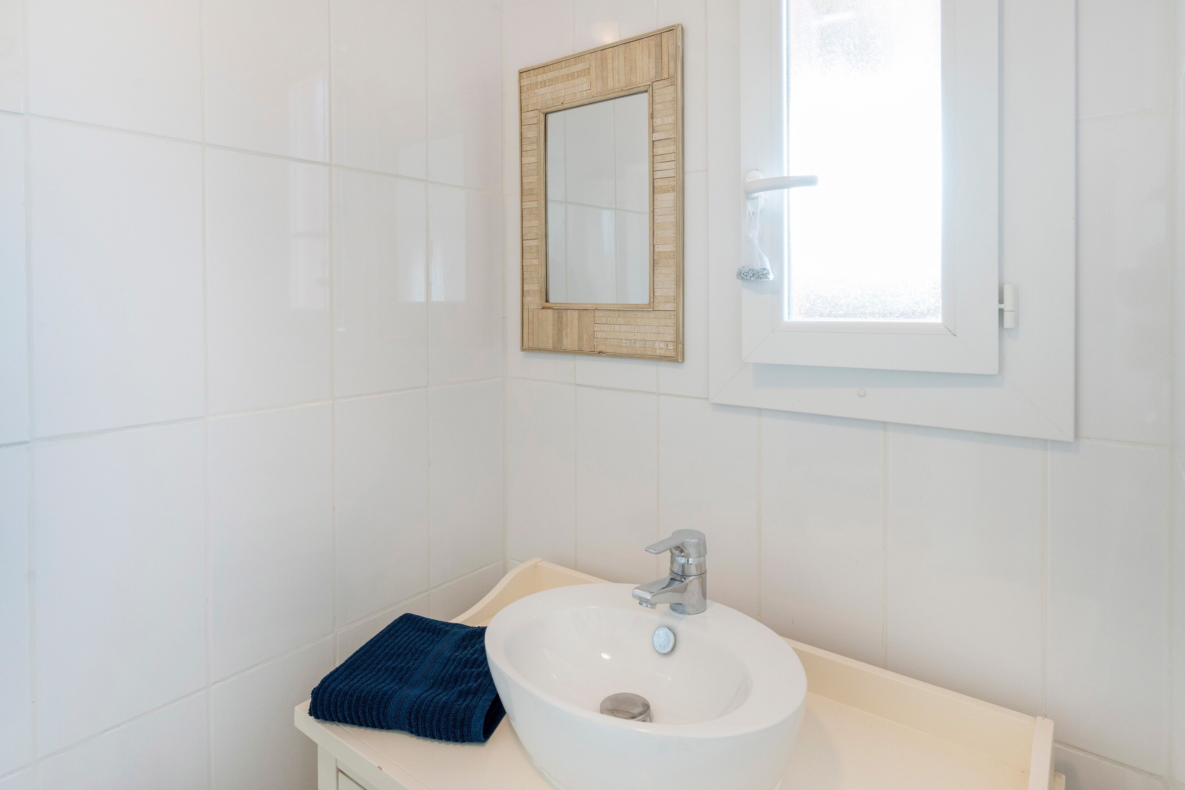 A bathroom with a white sink, a mirror, and a window.