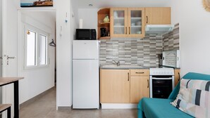Una cocina compacta con refrigerador, microondas, horno y armarios de madera.