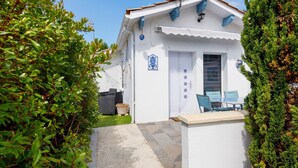 Un edificio blanco con un patio empedrado, mobiliario exterior y una puerta.