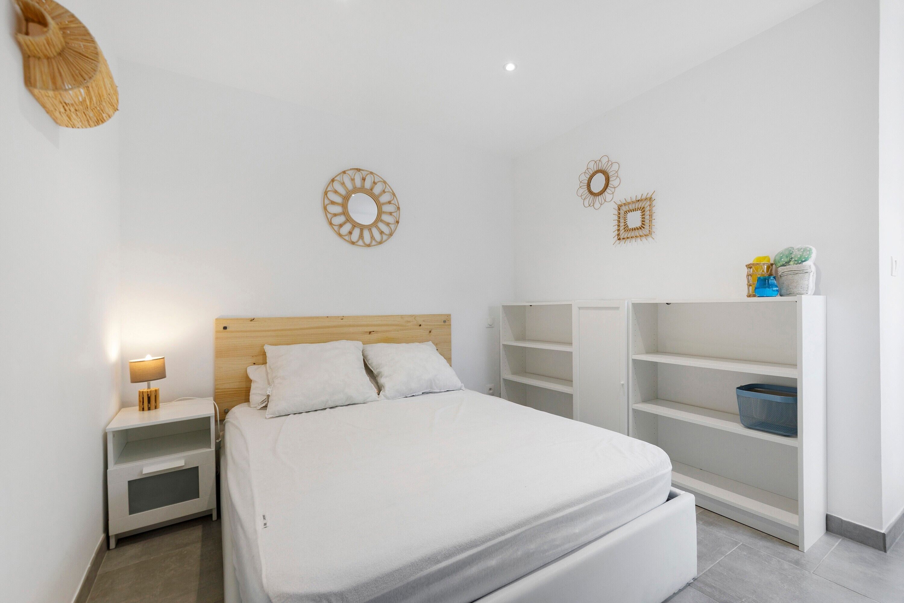 A bedroom with a bed, nightstand, and built-in shelving unit.