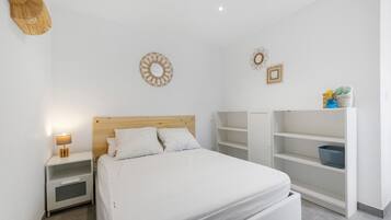 A bedroom with a bed, nightstand, and built-in shelving unit.