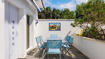 Une terrasse extérieure avec une table et des chaises, une porte et un tableau accroché au mur.