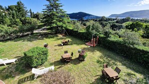 Ein Garten mit Gartenmöbeln, einer Schaukel und Blick auf einen See und Berge.