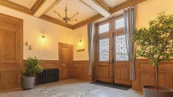 Ein Flur mit Holztüren, einem Heizkörper, einem gemusterten Teppich und einem Blumentopf.