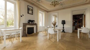 A spacious room with a fireplace, white furniture, and a bookshelf.