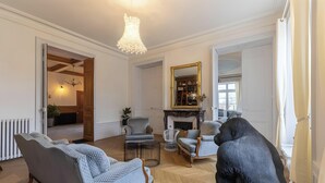 A spacious living room with a fireplace, a chandelier, and a large mirror.