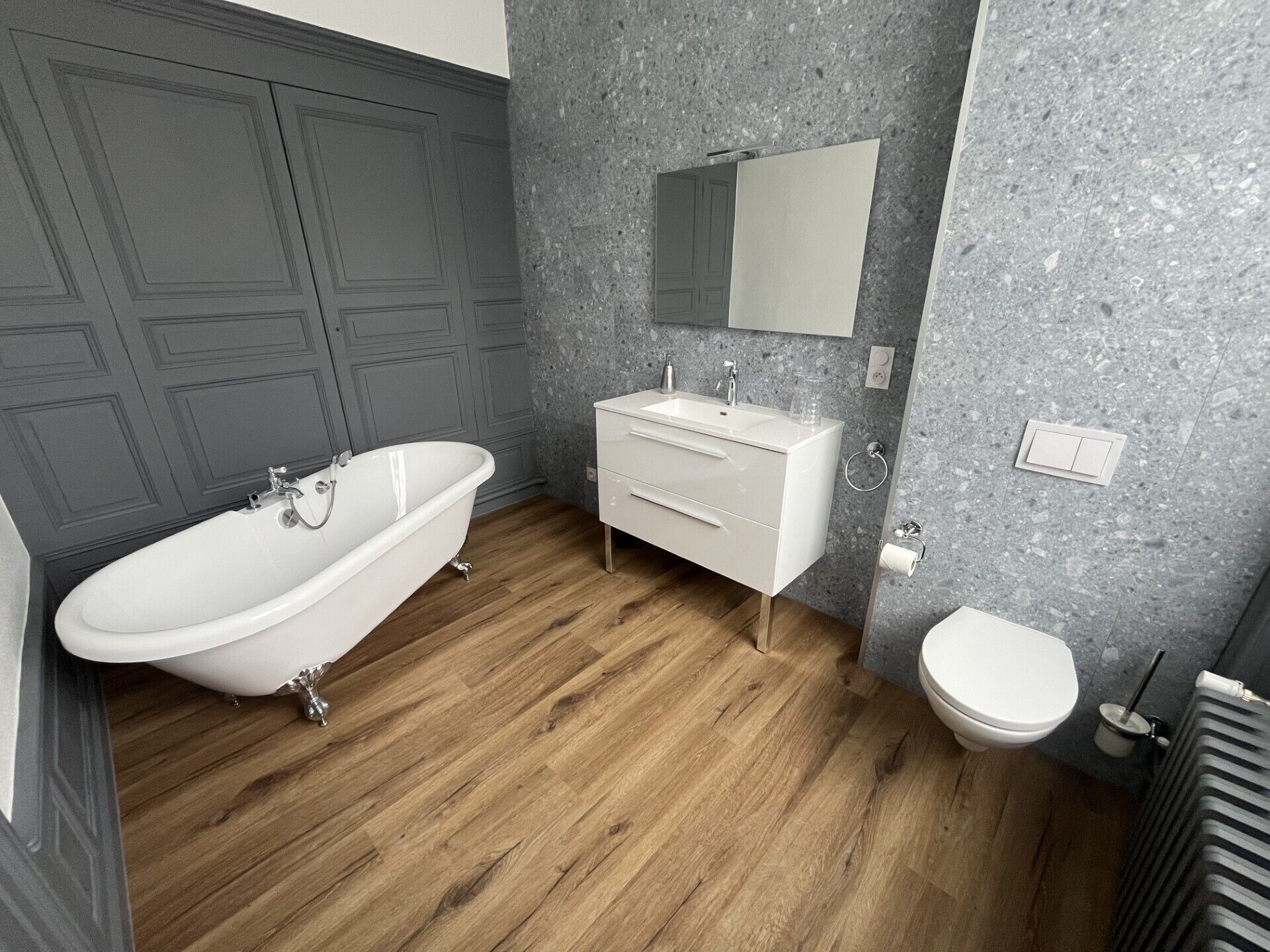 Une salle de bain avec une baignoire sur pieds, un meuble-lavabo blanc avec un miroir et des toilettes.
