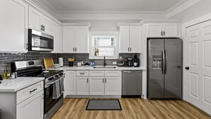 A modern kitchen with white cabinetry, a stainless steel refrigerator, a built-in oven, and a microwave.
