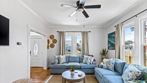 A living room with a blue sofa, a round coffee table, and a ceiling fan.