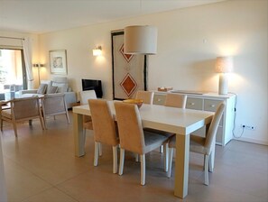 A modern dining area with a white table, beige chairs, and a decorative wall piece.