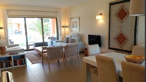 Un salon comprenant un canapé, des fauteuils, un téléviseur et un coin repas avec une table et des chaises.