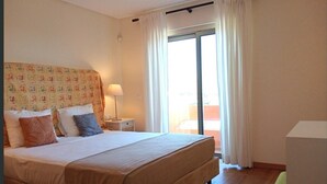 Une chambre d’hôtel avec un lit, une table de chevet, une lampe et une vue sur l’extérieur.