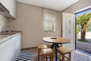 Une cuisine avec un coin repas, une fenêtre avec des rideaux et une vue sur l’extérieur.