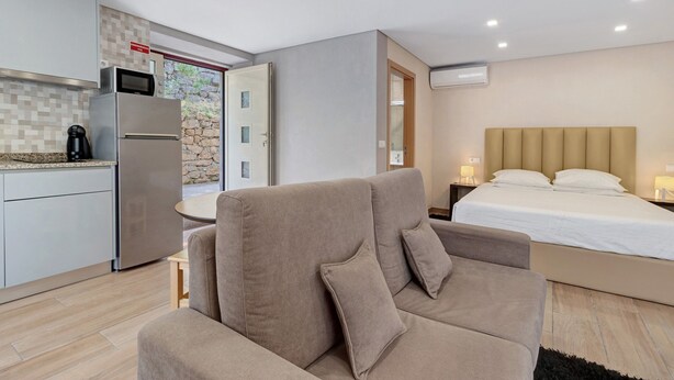 A compact room with a kitchenette, a bed with a headboard, and a sofa. - Apartment 'E' with Mountain View, Wi-Fi and Air Conditioning (Geres)
