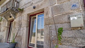 A stone building with a red-framed window, a potted plant, and a utility box with a label. - Apartment 'E' with Mountain View, Wi-Fi and Air Conditioning (Geres)