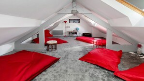 Ein kleiner Dachzimmer mit geneigter Decke, einem Fenster und einer kleinen Schreibtischzeile.