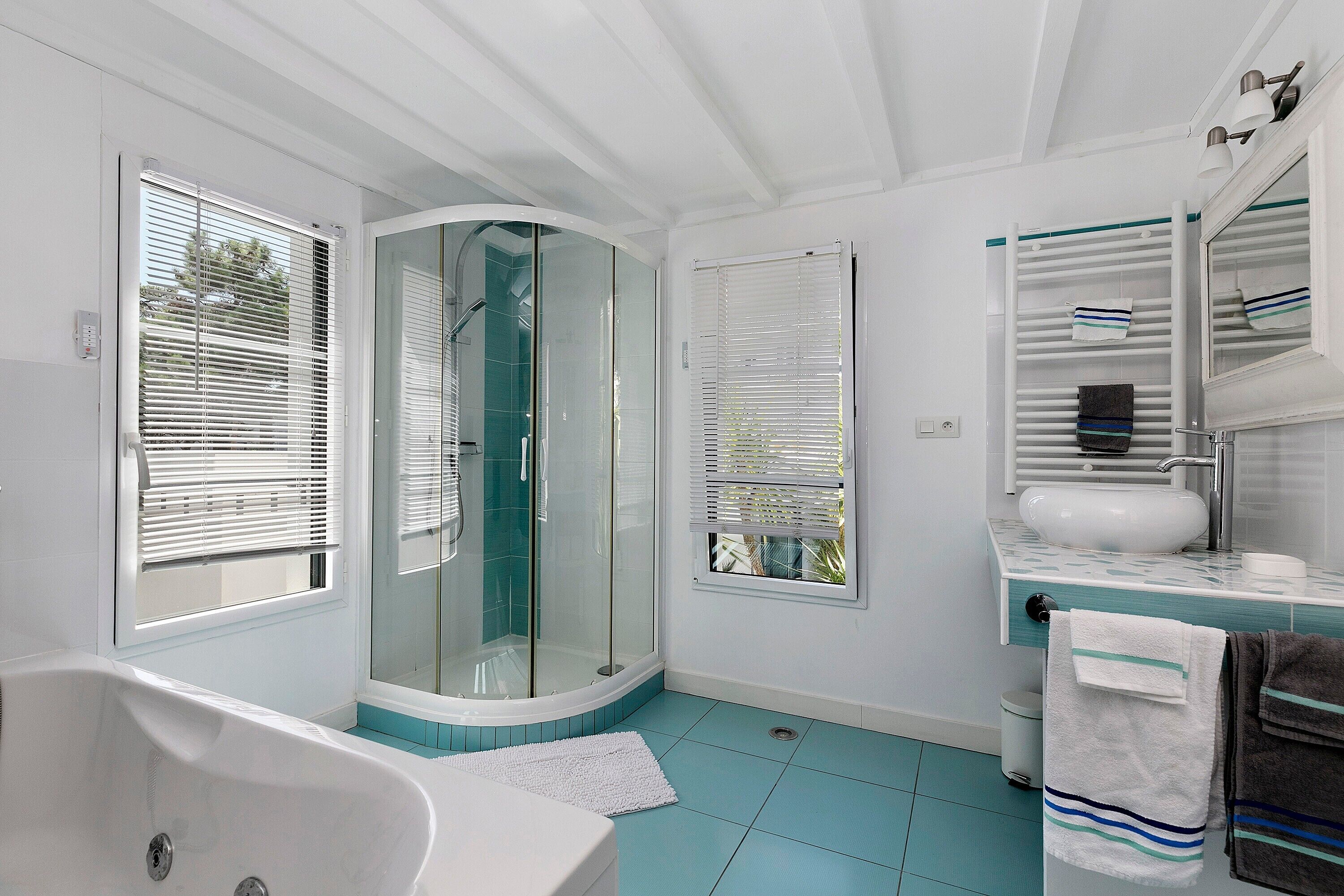 A bathroom with a bathtub, a glass shower enclosure, a sink, and a towel rack.