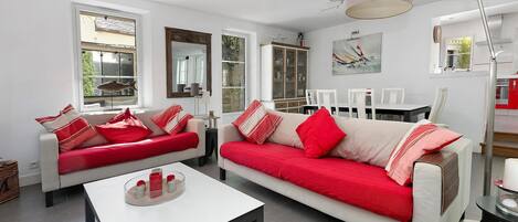 Una sala de estar moderna con dos sofás, una mesa de centro y una zona de comedor con sillas.