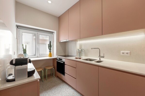 A modern kitchen with a built-in oven, a sink, and a window with a view of the outside. - The Great Rose Retreat (Nazaré)