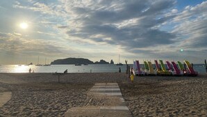 A beach with a wooden walkway, boats in the water, and a distant hill. - Apartment with terrace and pool in L'Estartit. (Torroella de Montgrí)