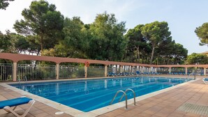 A swimming pool with a tiled deck, lounge chairs, and a covered area with a railing. - Apartment with terrace and pool in L'Estartit. (Torroella de Montgrí)