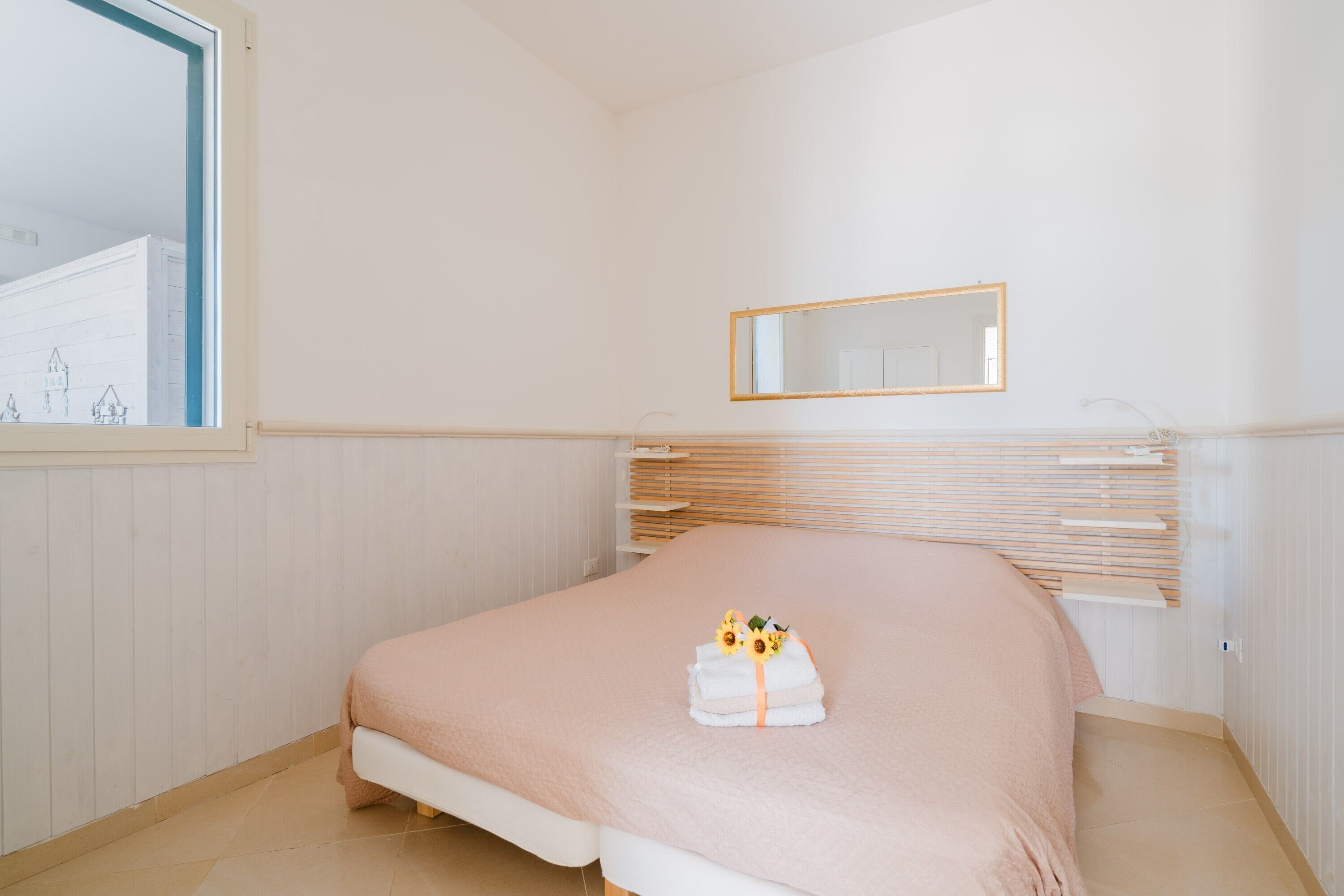 A bedroom with a bed, a window, a mirror, and a radiator.