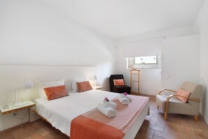 A hotel room with a bed, two chairs, a desk, and a window.