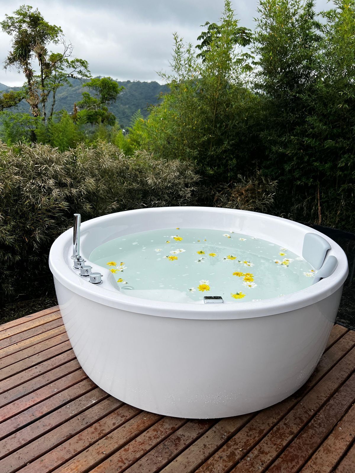 A white hot tub on a wooden deck with a natural landscape in the background.