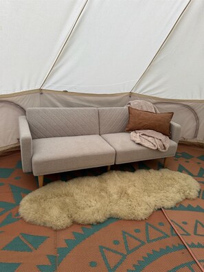 Un canapé avec une couverture et des coussins, dans une pièce qui ressemble à une tente.